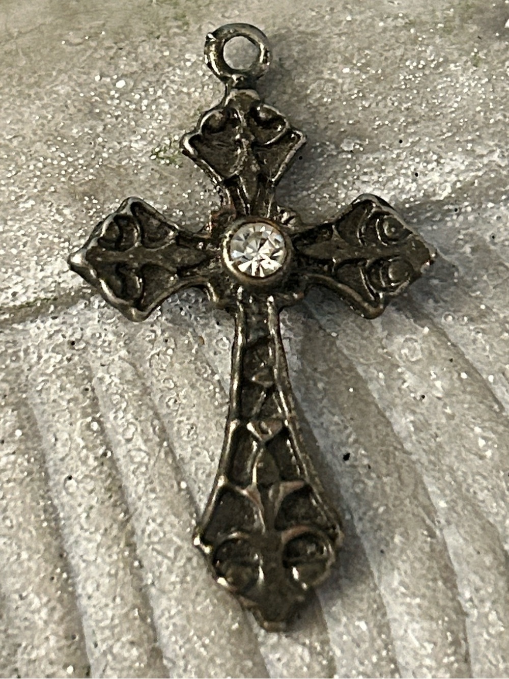 Cross pendant with a crystal center and silvertone scrollwork